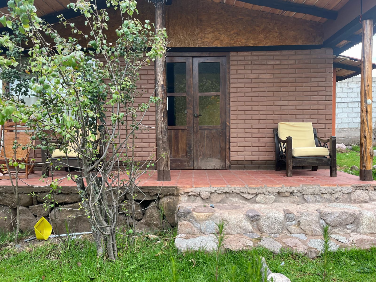 Entrada del bungalow de ladrillo con porche y sillones